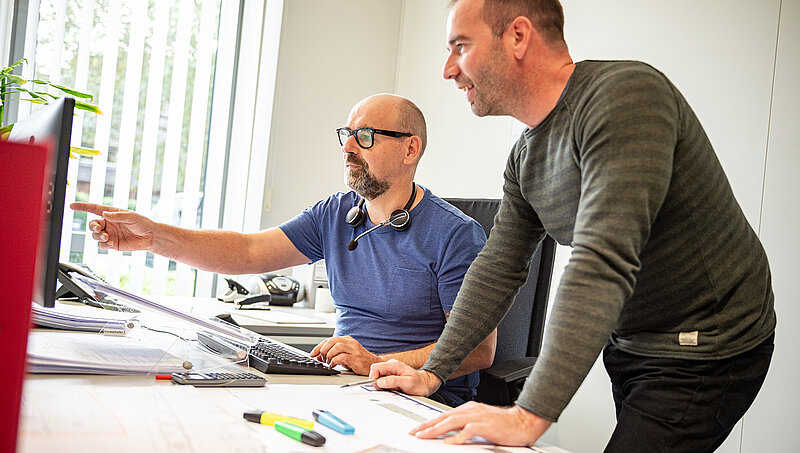 Zwei Mitarbeitende schauen auf einen Bildschirm
