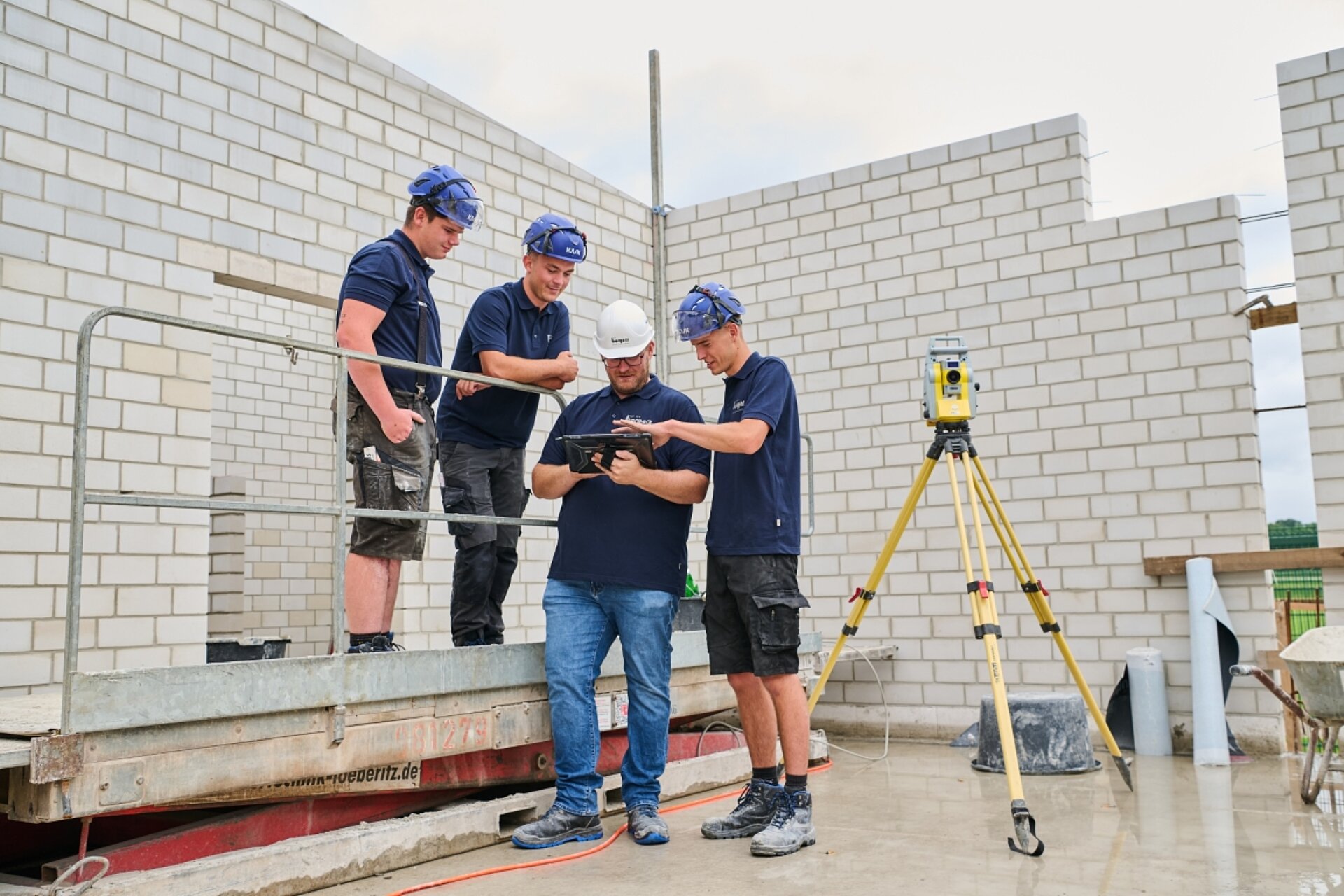 vier gewerbliche Mitarbeiter der Borgers GmbH auf einer Baustelle, die gemeinsam auf ein Tablett schauen