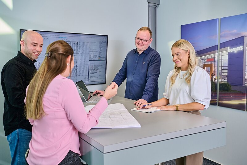 Vier Mitarbeiter der Borgers GmbH unterhalten sich. Es ist ein Bildschirm mit Plänen im Hintergrund zu sehen.