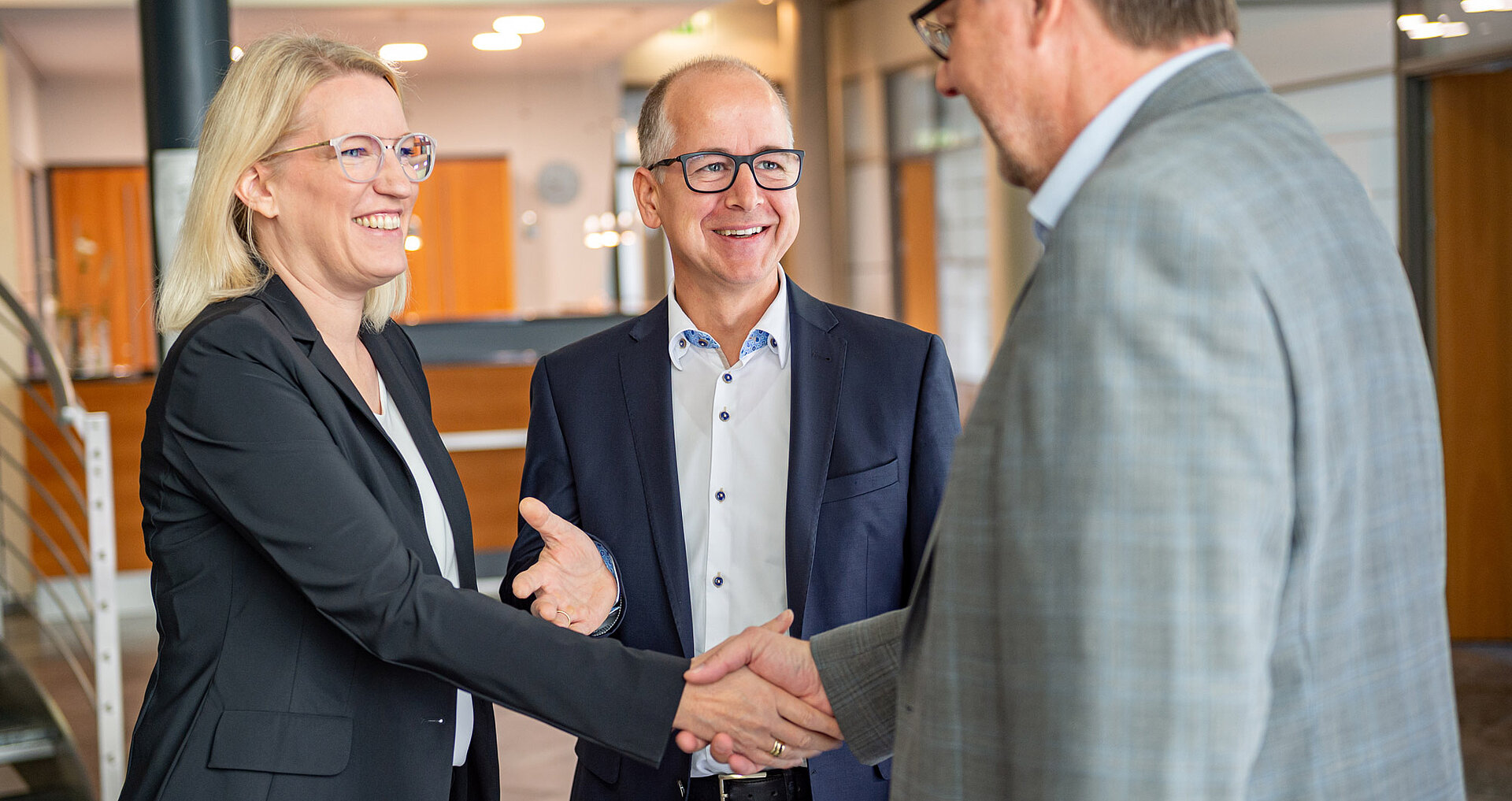 Die Geschäftsleitung reicht einem Herrn partnerschaftlich die Hand